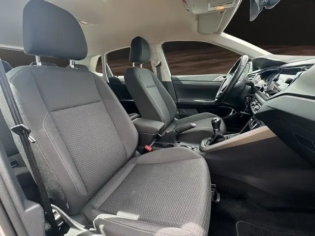 Intérieur avant gris foncé d'une Volkswagen Polo 1.0 TSI 95 Lounge Business, vue côté conducteur avec volant multifonctions et boîte manuelle.