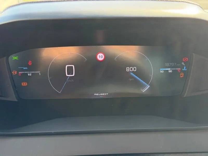 Tableau de bord numérique de Peugeot 208 1.2 100ch blanc, affichant vitesse à 0 km/h et régime moteur à 800 rpm.