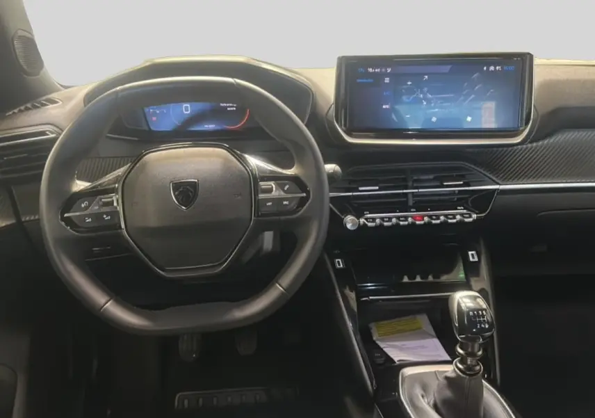 Vue intérieure frontale du tableau de bord et volant noir d'une Peugeot 2008 1.2 100 allure avec boîte manuelle.