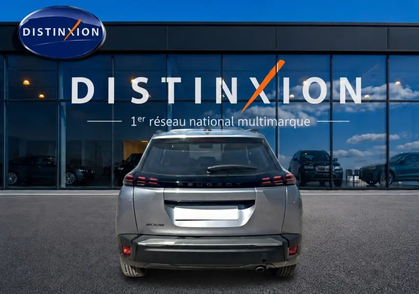 Vue arrière d'un Peugeot 2008 gris artense garé devant une vitrine avec logo Distinxion en arrière-plan.