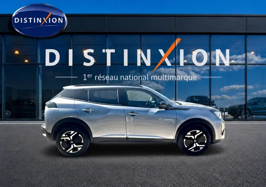 Peugeot 2008 1.2 100 Allure gris Artense vue de profil côté gauche devant une vitrine Distinxion.