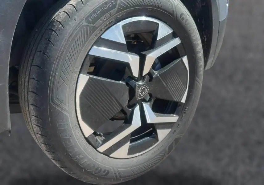 Gros plan sur la roue avant gauche du Peugeot 2008 gris Artense avec jante alu au design moderne et logo central lion.