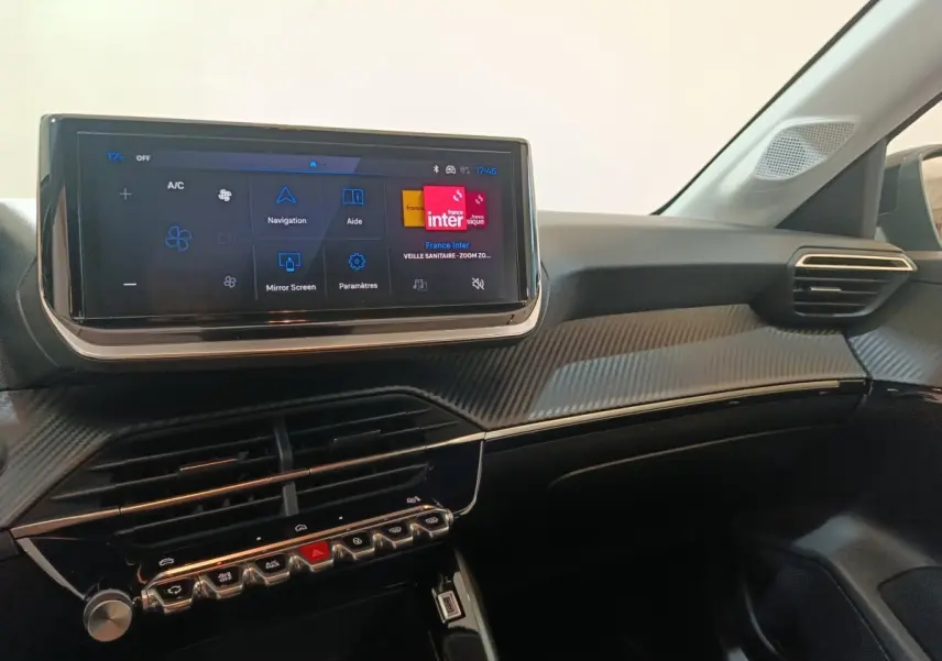 Vue intérieure du tableau de bord de la Peugeot 208 Hybrid 100 e-DCS6 Style 2025 avec écran tactile et finition carbone.