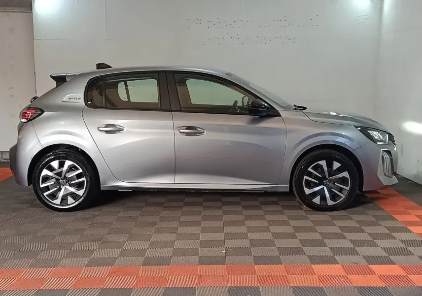 Peugeot 208 Hybrid gris clair vue de profil côté gauche, avec jantes alliage et badge Style visible à l'arrière.