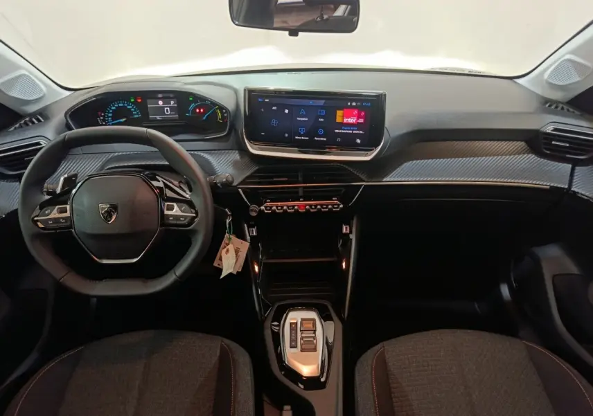 Vue intérieure frontale du tableau de bord et volant cuir noir de la Peugeot 208 Hybrid 2025 avec écran tactile central.