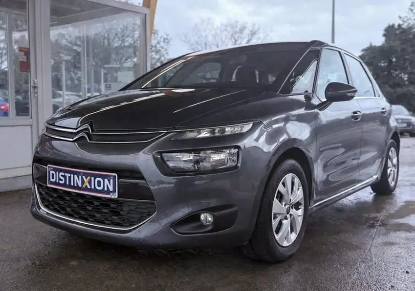 Vue 3/4 avant droit d'une Citroën C4 Picasso gris platinium métallisé avec calandre distinctive et feux LED fins.