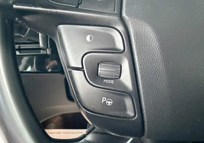 Gros plan sur les commandes au volant noir de la Citroën C4 Picasso gris platinium, côté gauche du volant.