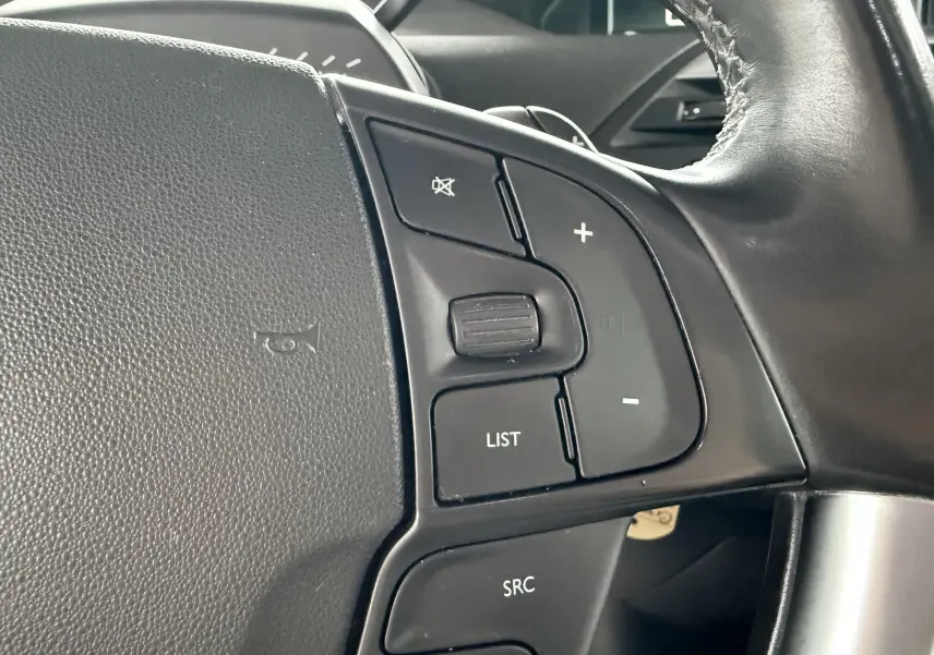 Gros plan sur les commandes du volant noir de la Citroën C4 Picasso 2015, avec boutons de volume et fonction liste.