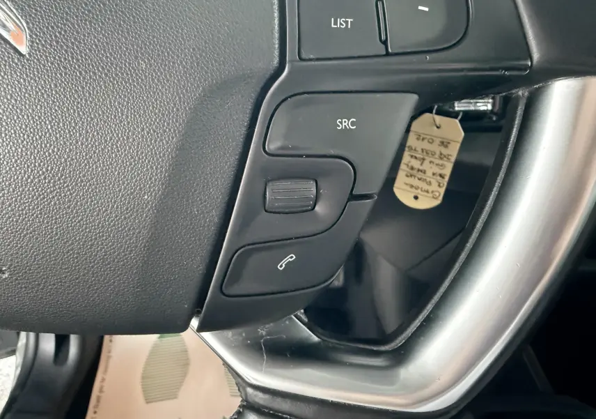 Gros plan sur les commandes au volant gris et noir de la Citroën C4 Picasso 2015, côté gauche.