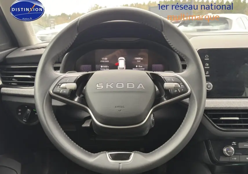 Vue centrée sur le volant cuir noir SKODA avec tableau de bord numérique et écran tactile à droite.