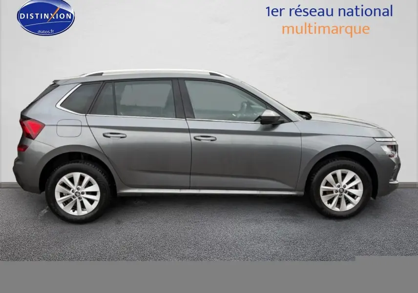 Vue latérale droite d'un Skoda Kamiq gris 2025 avec jantes alliage et barres de toit blanches.