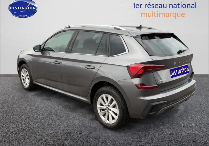 Vue 3/4 arrière droite d'un Skoda Kamiq gris 2025 avec barres de toit et feux arrière LED distinctifs.