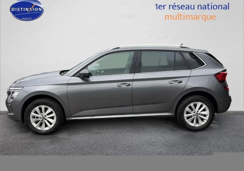 Profil côté gauche d'un Skoda Kamiq gris 2025 avec jantes alu et barres de toit visibles.