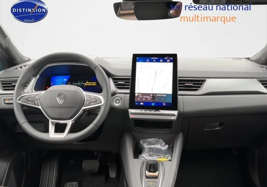 Vue intérieure avant du tableau de bord gris du Renault Symbioz 1.8 e-tech avec écran tactile vertical et volant multifonction.