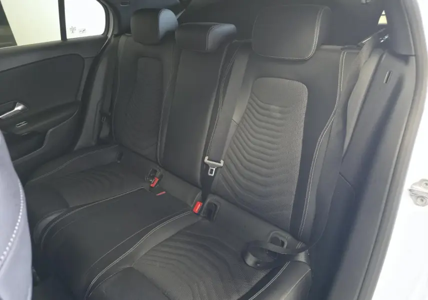 Vue intérieure arrière droite des sièges en tissu noir avec surpiqûres blanches d'une Mercedes Classe A 160 Style Line blanche.