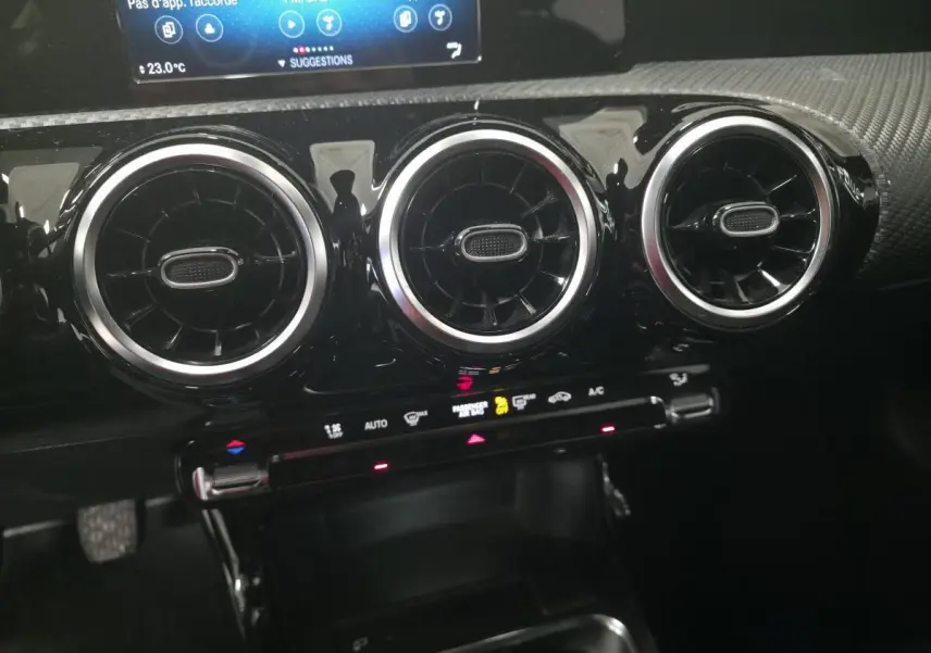 Détail du tableau de bord de la Mercedes Classe A 160 Style Line 2019 montrant les trois aérateurs ronds chromés et la console de climatisation.