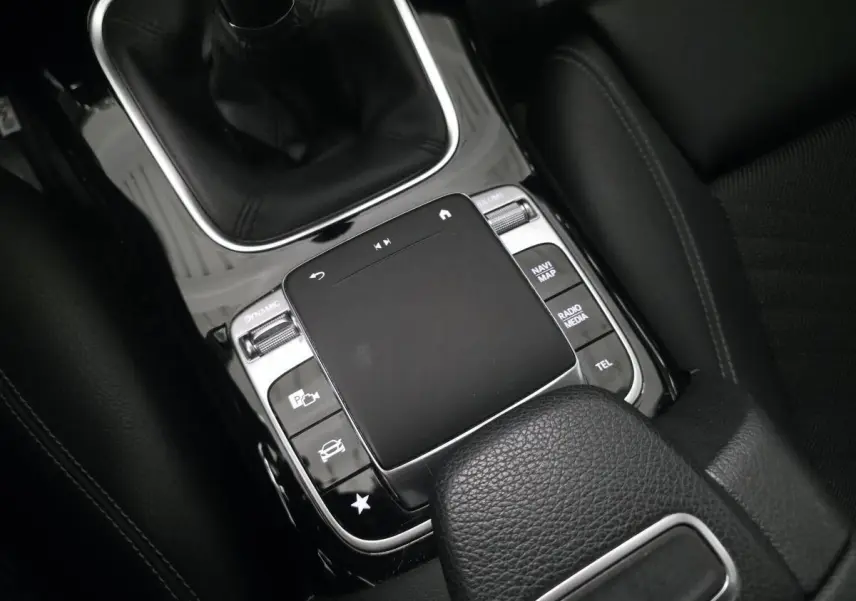 Gros plan sur la console centrale noire de la Mercedes Classe A 160 Style Line avec pavé tactile et levier de vitesses manuel.