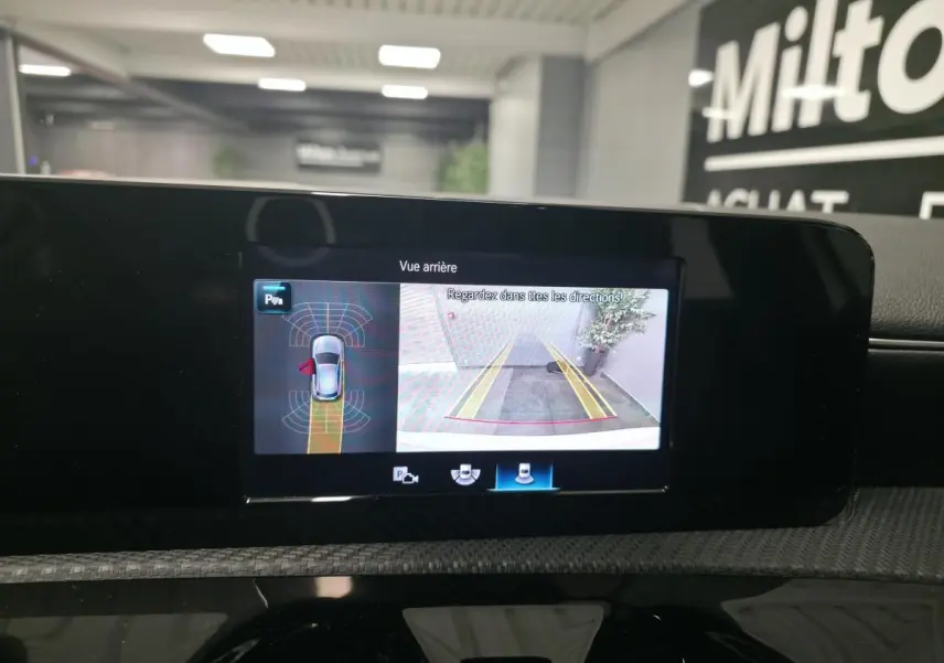 Écran multimédia intérieur montrant la caméra de recul et l’aide au stationnement d’une Mercedes Classe A blanche.