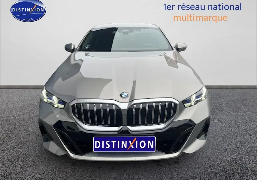 Vue avant d'une BMW Série 5 G60 gris métallisé avec calandre imposante et phares LED allumés.