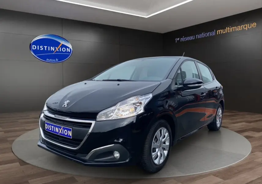 Peugeot 208 Affaire noir vue 3/4 avant droit, avec phares allumés et jantes argentées en showroom.