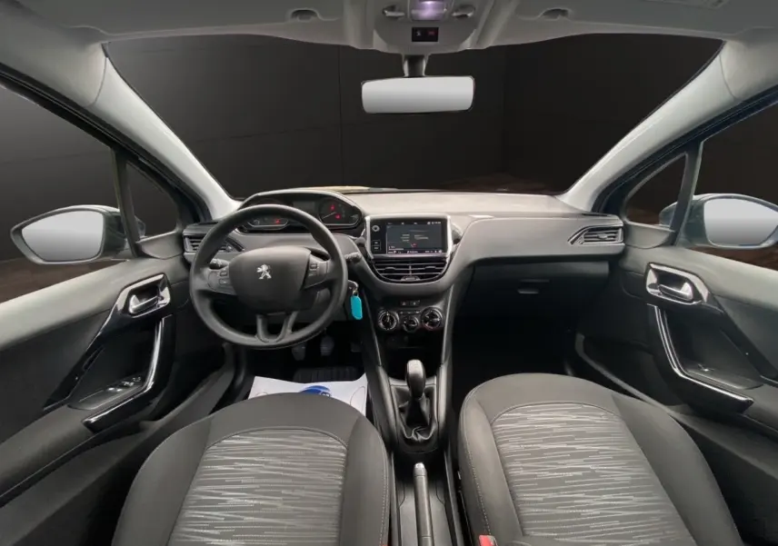 Vue intérieure frontale du poste de conduite de la Peugeot 208 Affaire noire avec tableau de bord tactile et volant multifonctions.
