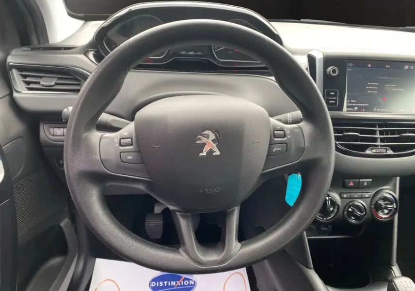 Vue intérieure centrée sur le volant Peugeot 208 noir avec tableau de bord et écran tactile à droite.