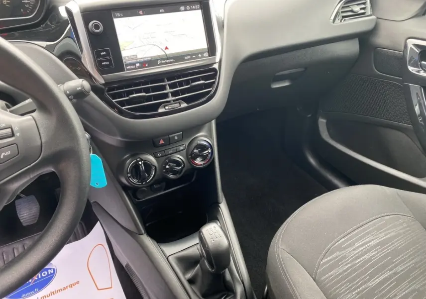Vue intérieure côté conducteur de la Peugeot 208 Affaire noire, avec tableau de bord tactile et levier de vitesses manuel.