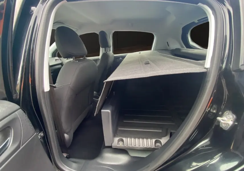 Vue intérieure côté gauche de la Peugeot 208 Affaire noire, montrant les sièges avant et l'espace de chargement avec cloison.