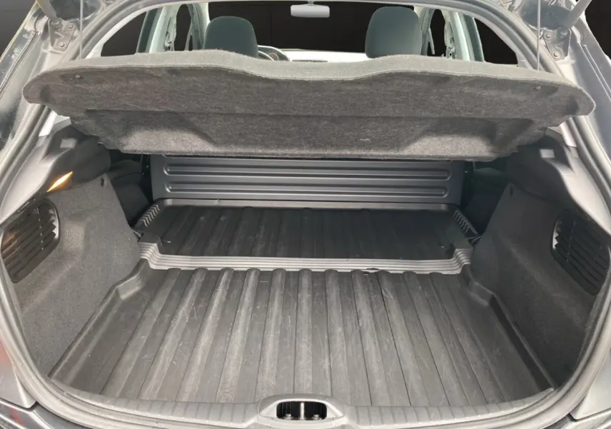 Coffre ouvert vu de l'arrière d'une Peugeot 208 Affaire noire, montrant l'espace de chargement avec tapis en caoutchouc.