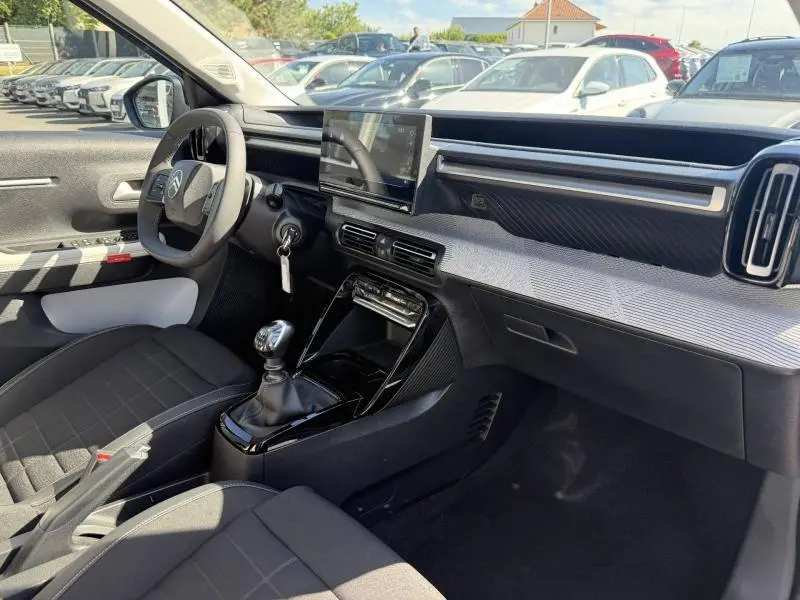 Intérieur avant droit de la Citroën C3 2025 avec tableau de bord moderne, écran tactile et boîte manuelle.
