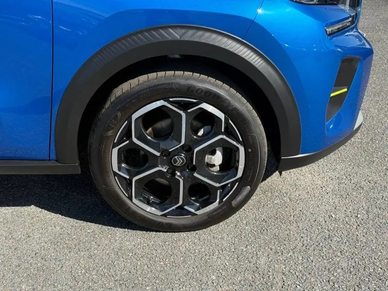 Gros plan sur la roue avant droite de la Citroën C3 Bright Blue avec jante alu au design hexagonal et partie avant du pare-chocs.