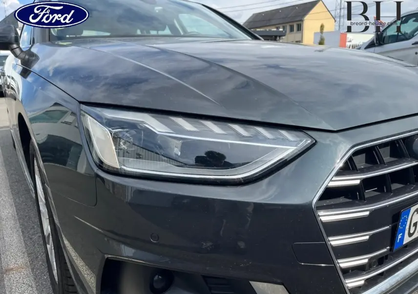 Gros plan sur l'avant droit de l'Audi A4 Avant gris Manhattan métallisé, mettant en valeur le phare LED et la calandre distinctive.