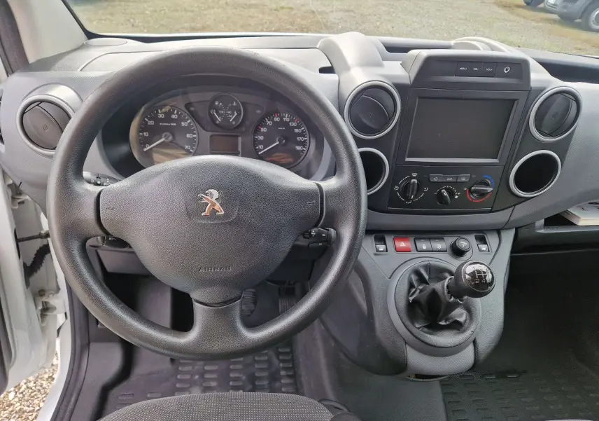 Vue intérieure du tableau de bord du Peugeot Partner blanc 2017, avec volant, levier de vitesse manuel et écran central éteint.