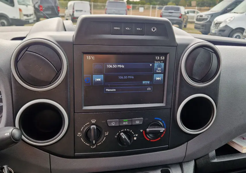 Vue rapprochée du tableau de bord noir du Peugeot Partner blanc 2017, avec écran central tactile et commandes de climatisation.