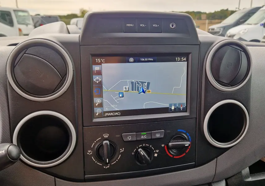 Vue rapprochée du tableau de bord du Peugeot Partner blanc 2017, avec écran GPS et commandes de climatisation visibles.