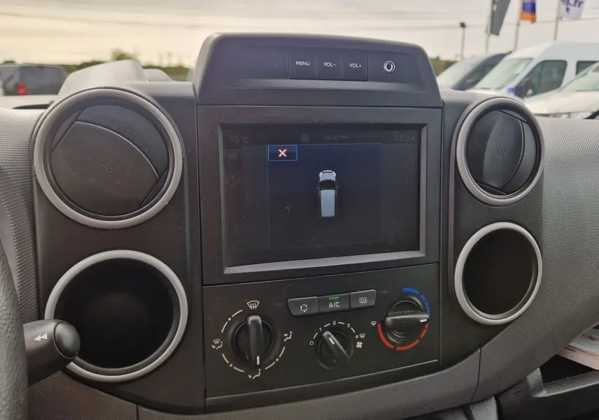 Vue rapprochée du tableau de bord du Peugeot Partner blanc 2017, mettant en valeur l’écran GPS et les commandes de climatisation.