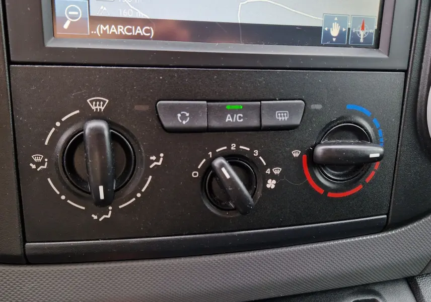 Gros plan sur les commandes de climatisation du Peugeot Partner blanc 2017, avec réglages manuels et affichage A/C allumé.