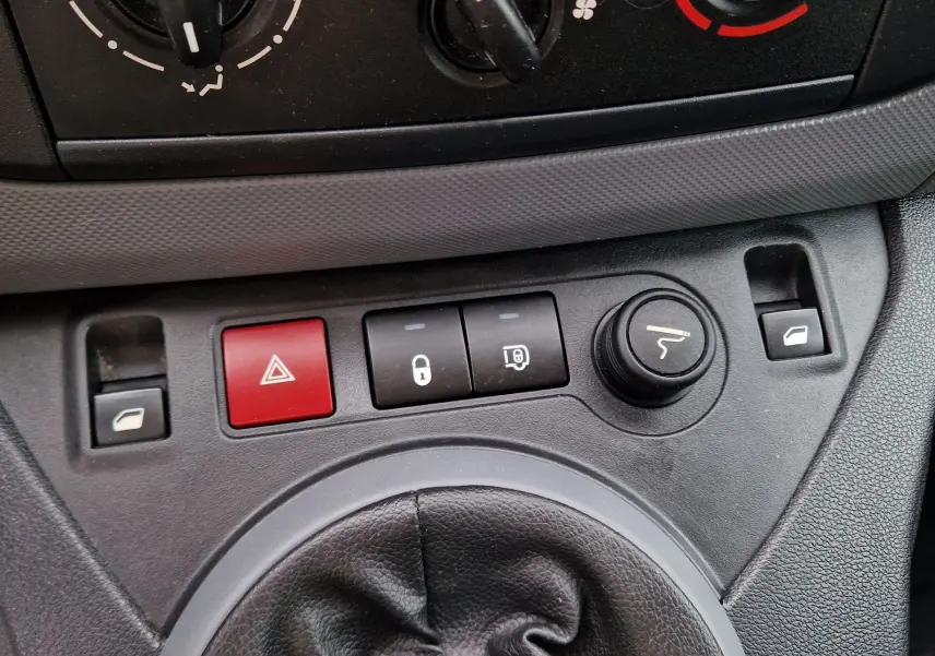 Gros plan sur la console centrale du Peugeot Partner blanc 2017, montrant les boutons de verrouillage, warning et réglage des rétroviseurs.