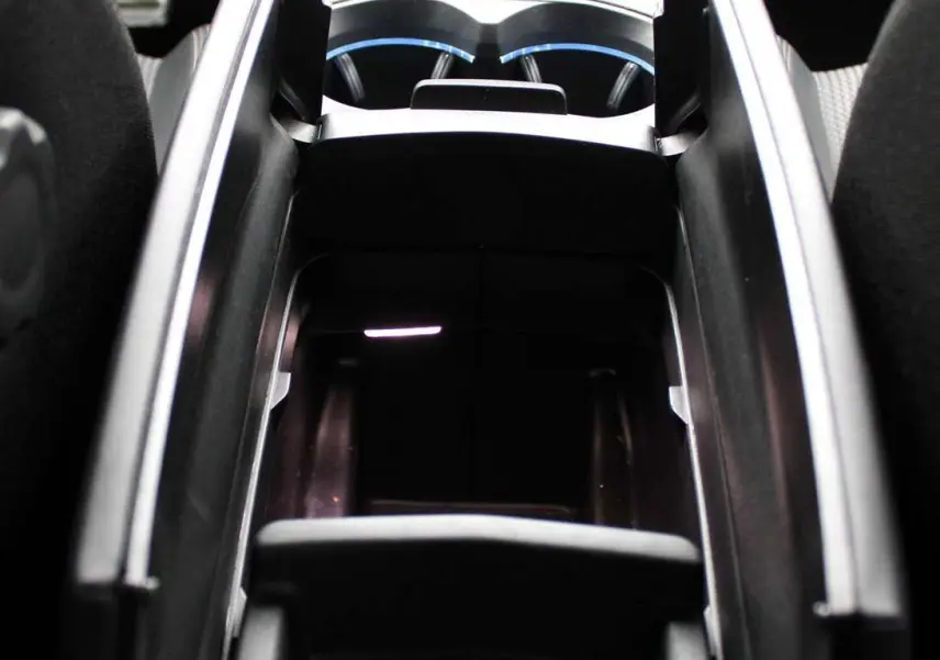 Vue rapprochée de la console centrale noire du Peugeot 3008 2025 avec porte-gobelets et rangement ouvert.