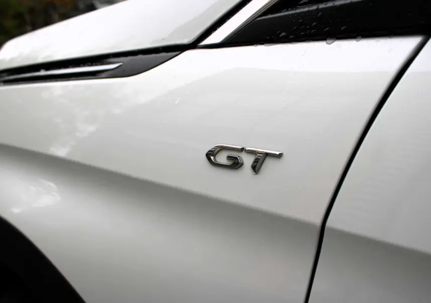 Gros plan sur l’inscription GT côté gauche d’un Peugeot 3008 blanc nacré avec détails de carrosserie.