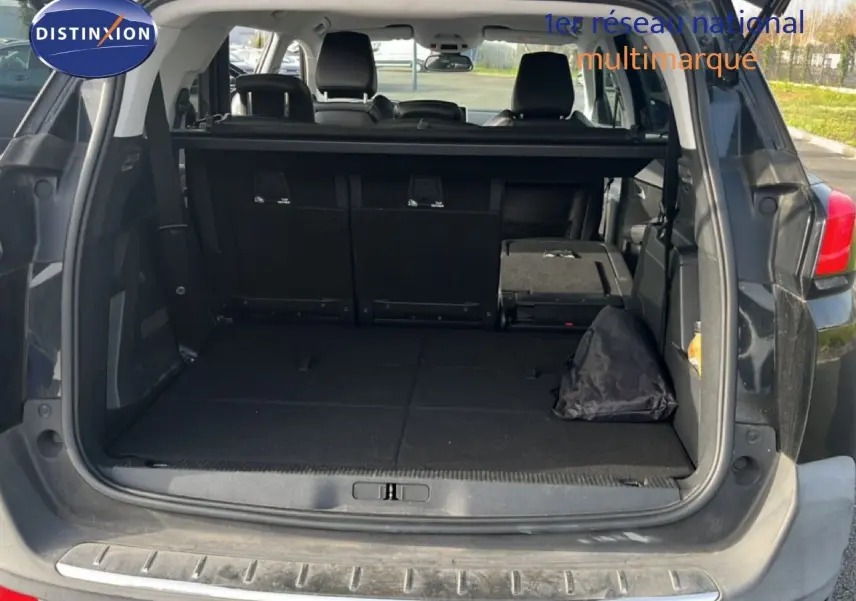 Coffre ouvert en vue arrière d’un Peugeot 5008 noir Perla Nera, montrant l’espace de chargement et sièges rabattus.