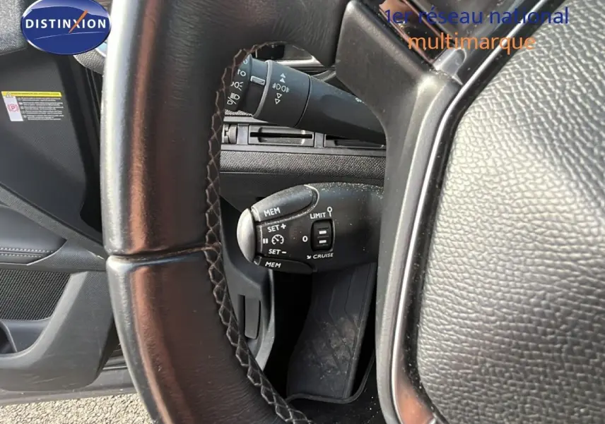 Gros plan sur le volant en cuir noir et la commande de régulateur de vitesse du Peugeot 5008 noir Perla Nera, vue côté conducteur.