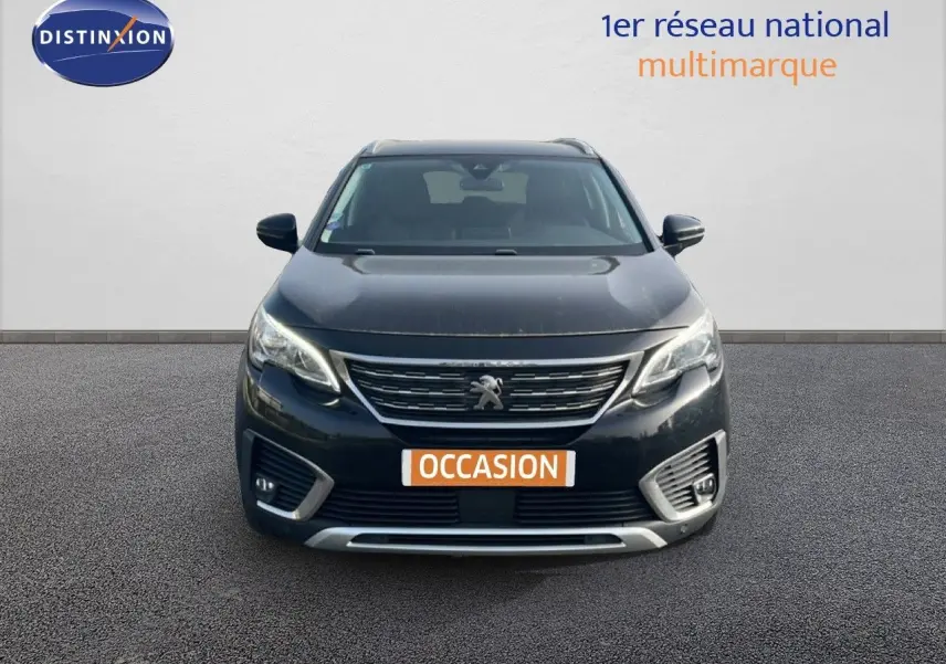 Vue frontale d’un Peugeot 5008 noir Perla Nera avec calandre chromée et feux LED allumés sur fond neutre.