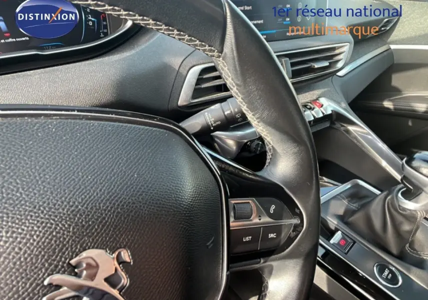 Vue rapprochée de l’intérieur du Peugeot 5008 noir, montrant le volant cuir, la console centrale et le levier de vitesse manuel.