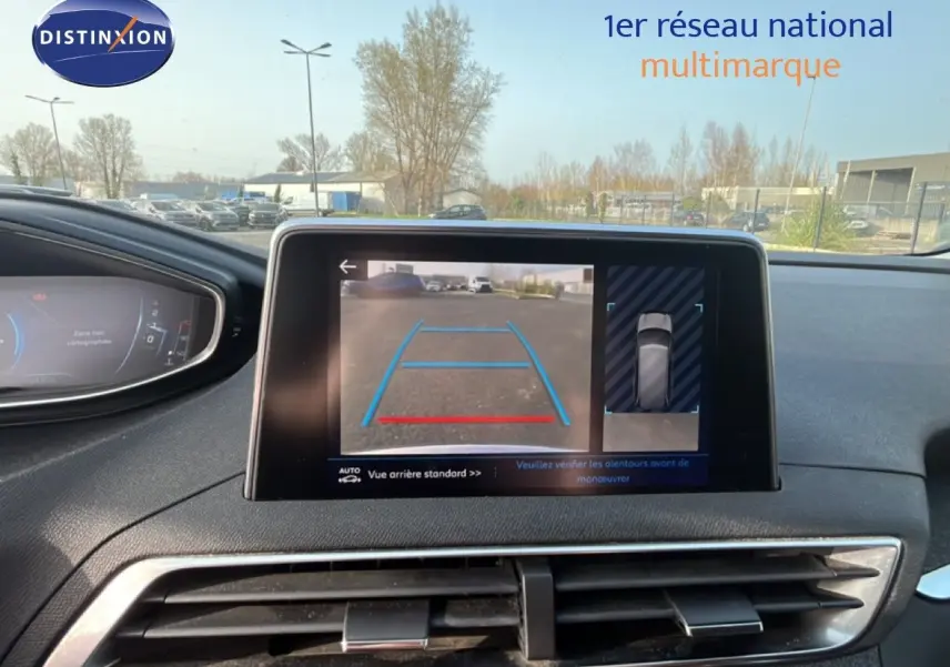 Vue intérieure du tableau de bord du Peugeot 5008 noir, avec écran central affichant la caméra de recul en marche.