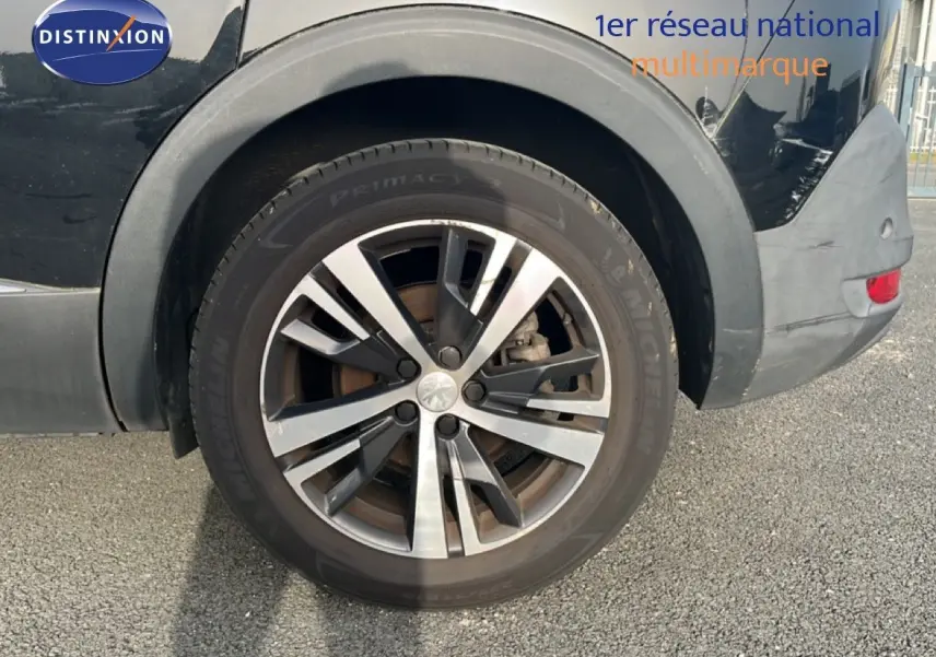 Gros plan sur la roue arrière droite d’un Peugeot 5008 noir Perla Nera, jante alliage bicolore 18 pouces.