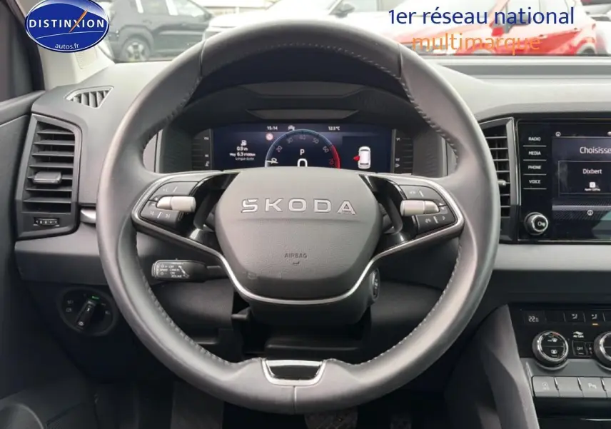 Vue intérieure centrée sur le volant cuir SKODA avec tableau de bord numérique et écran tactile à droite.