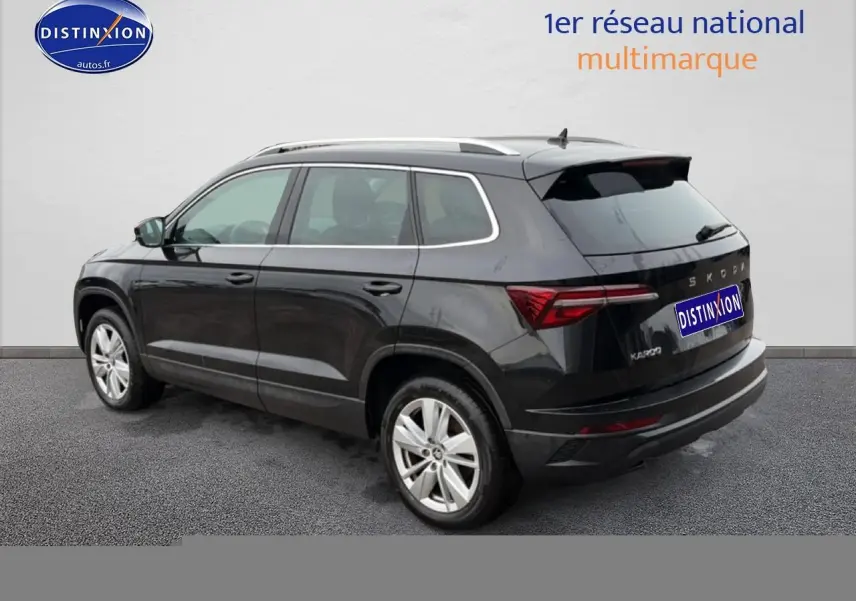 Vue 3/4 arrière droite d'un Skoda Karoq noir 2025 avec barres de toit et feux arrière LED distinctifs.