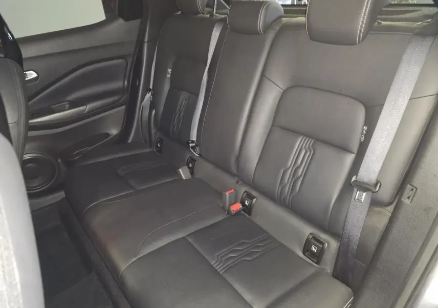 Vue intérieure de la banquette arrière en cuir noir du Nissan Juke 2024, avec ceintures de sécurité et appuis-tête réglables.