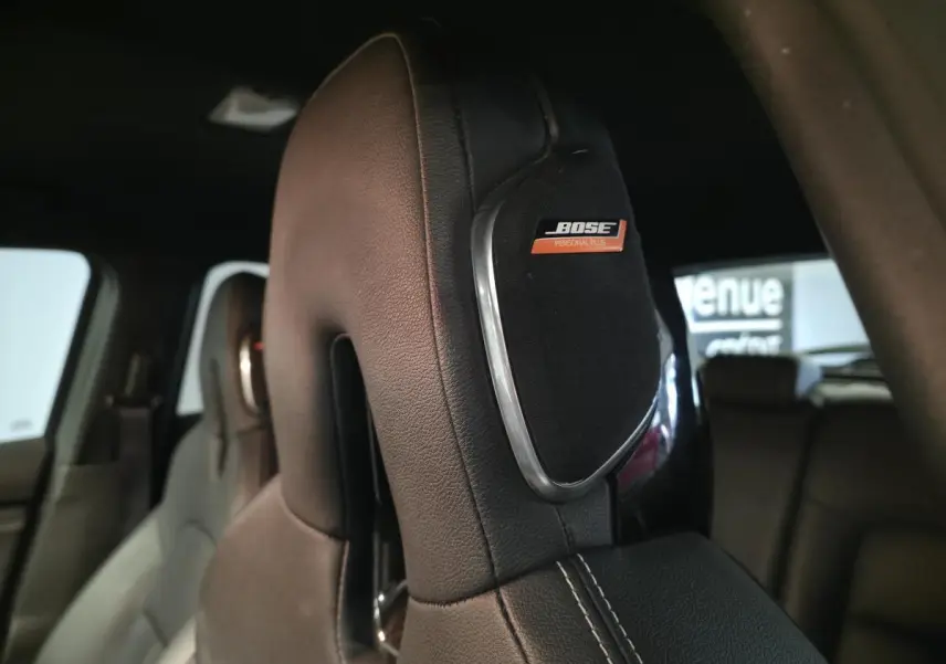 Gros plan sur l’appui-tête avant en cuir noir avec haut-parleur Bose intégré dans un Nissan Juke 2024.